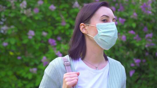 公园花卉植物背景下戴医用口罩的年轻女子肖