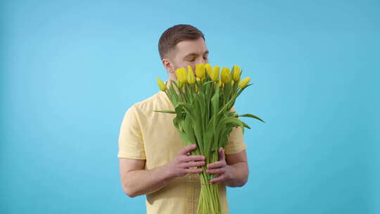 一名男子站在黄色郁金香的蓝色背景前，看着