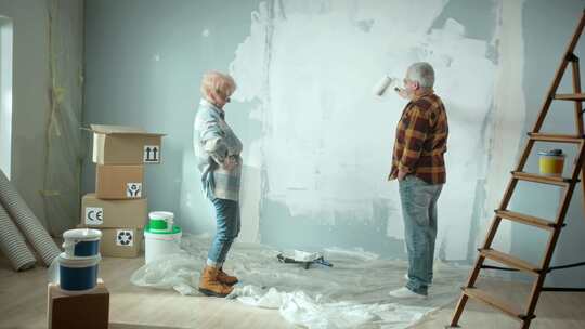 老人用油漆滚筒用白色油漆粉刷墙壁