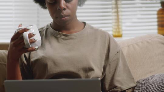 女人坐在沙发上用笔记本电脑打字视频素材模板下载