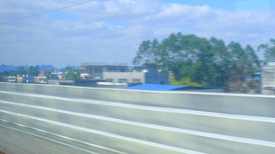 高速行驶中的高铁动车窗外城镇自然风光