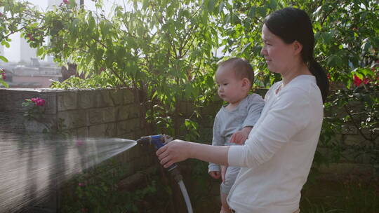 妈妈抱着小宝宝在花园里浇水