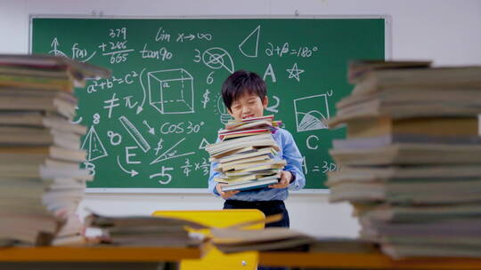 在教室里抱着一摞书的小学生