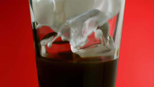 奶油与冰和咖啡混合在红色背景的玻璃杯中