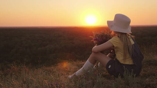 女孩坐在草地上欣赏日落视频素材模板下载