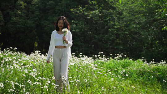 美女手握鲜花漫步草地沐浴阳光慢镜头特写