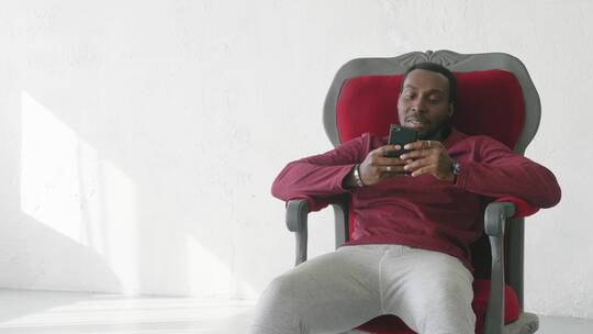 坐在椅子上玩手机的男人视频素材模板下载