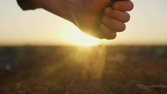 农民拿干燥的土壤浇灌地面手部特写反对日出