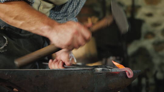 铁匠的手用锤子敲打铁砧制造锻造产品的慢动作