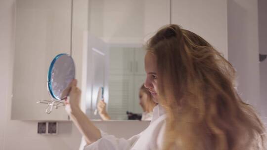 拿着镜子整理头发的女人
