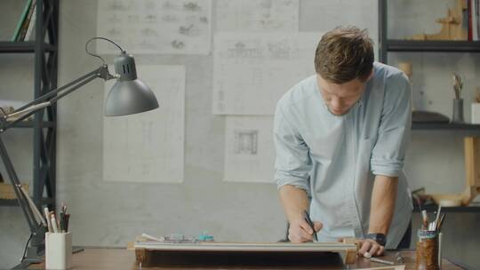 男人站在办公桌前画设计图