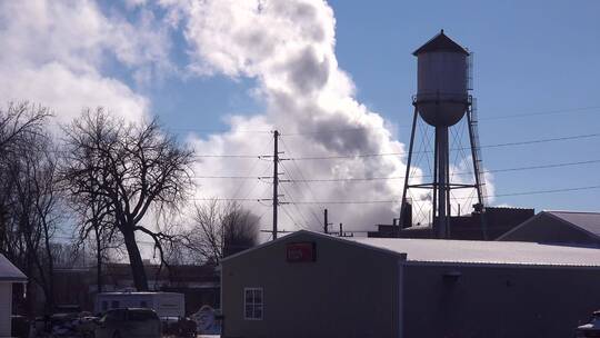 工厂的烟雾从水塔后面喷涌而出