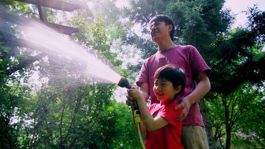 快乐父子在院子里浇水视频素材模板下载