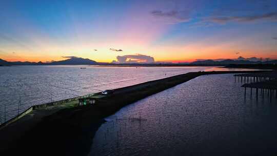 航拍夕阳下汽车开灯行驶在有晚霞的海边