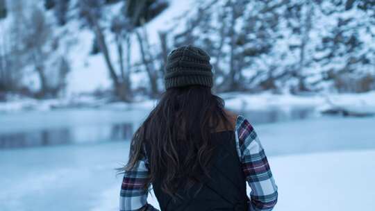 雪中走过池塘的女人