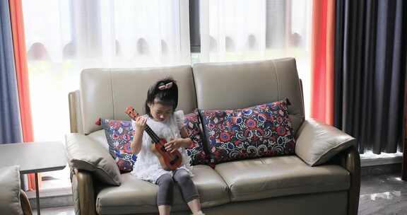 小女孩坐在沙发上玩乐器