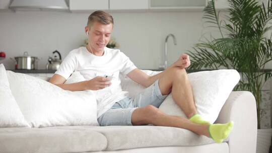 男人在沙发上玩手机视频素材模板下载