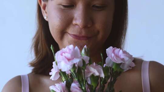 拿着花闻着花的女人