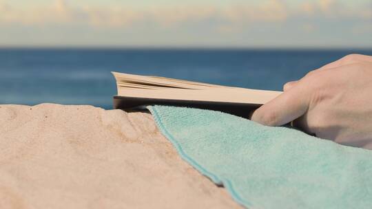 在沙滩上翻阅书籍的手微距场景