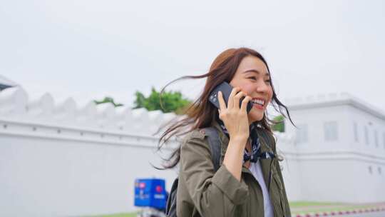 亚洲有魅力的女背包客在城市度假时边走边打电话。