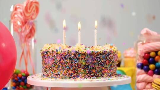 桌子上的生日蛋糕上放着糖果和气球