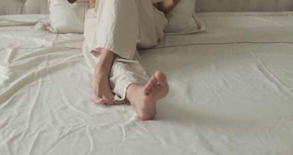 女性坐于卧室床上的居家场景