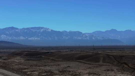 大气航拍西北戈壁滩上的公路及远方的雪山