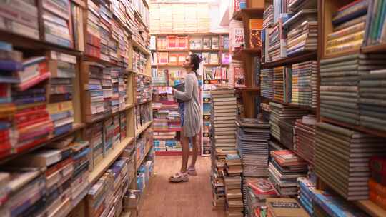 女孩站在书架之间找书