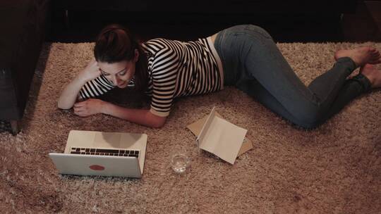 女人躺在地毯上看笔记本电脑