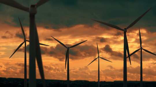 美丽的橙色日落下的风力涡轮机农场。美丽晴朗的生态能源发电机