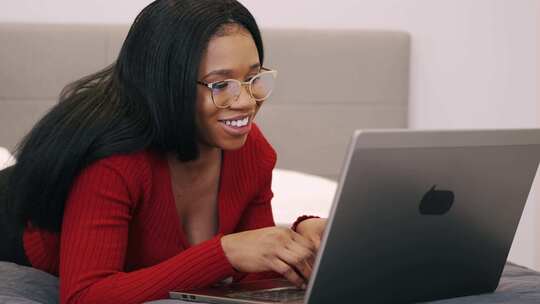 非裔女性在床上使用笔记本电脑