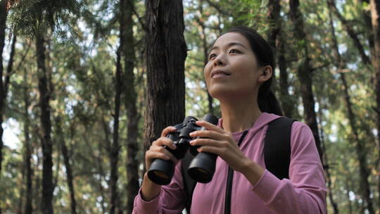 亚洲中国人女性森林树林旅游拿望远镜看风景