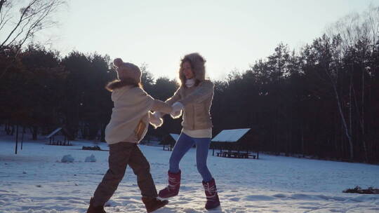 妈妈和女儿在雪地里拉着手跳舞