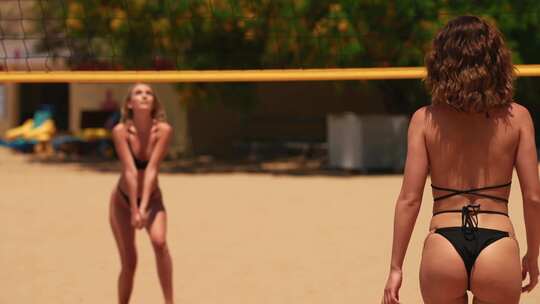 两个比基尼美女在海边沙滩打排球