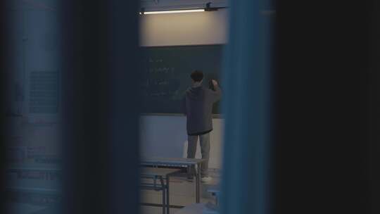 夜晚教室学生在黑板写字