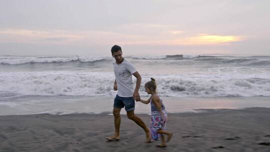 父亲和女儿在沙滩上跑步