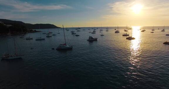 海岸海水视频夕阳下大海里游泳的游客帆船