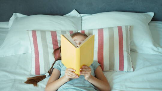 躺在床上看书的女孩视频素材模板下载