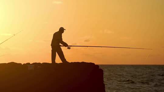 男人在夕阳下的海边钓鱼