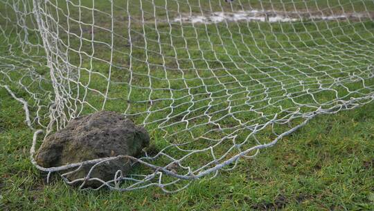 足球被踢进用石头按住的球门网里视频素材模板下载