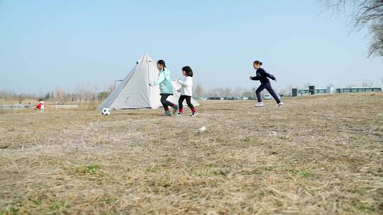 冬季在公园草坪上踢球的三个女孩