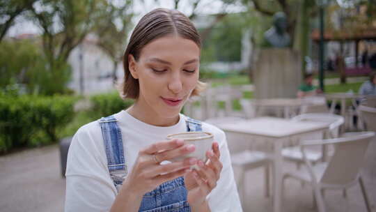 微笑的女士在咖啡馆露台喝卡布奇诺特写肖像