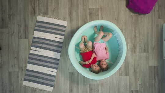 兄弟和姐妹躺在浅游泳池靠近地毯上地板