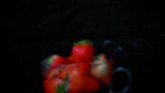 草莓落入玻璃杯中溅起水花的慢镜头