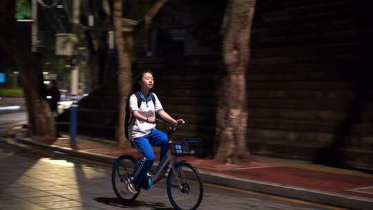 晚上下课后放学女学生骑自行车背影青春时代