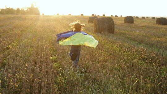 女孩披着旗帜在田野里奔跑