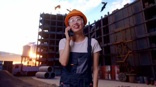 亚洲女工在智能手机上聊天，环顾建筑工地