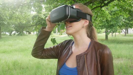 女人在公园里使用现代虚拟现实眼镜视频素材模板下载