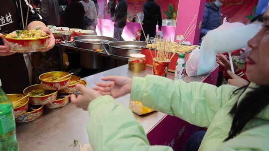 小吃摊前顾客伸手接递来的食物