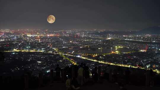 山顶赏月看城市风景中秋节月亮山上赏月人群